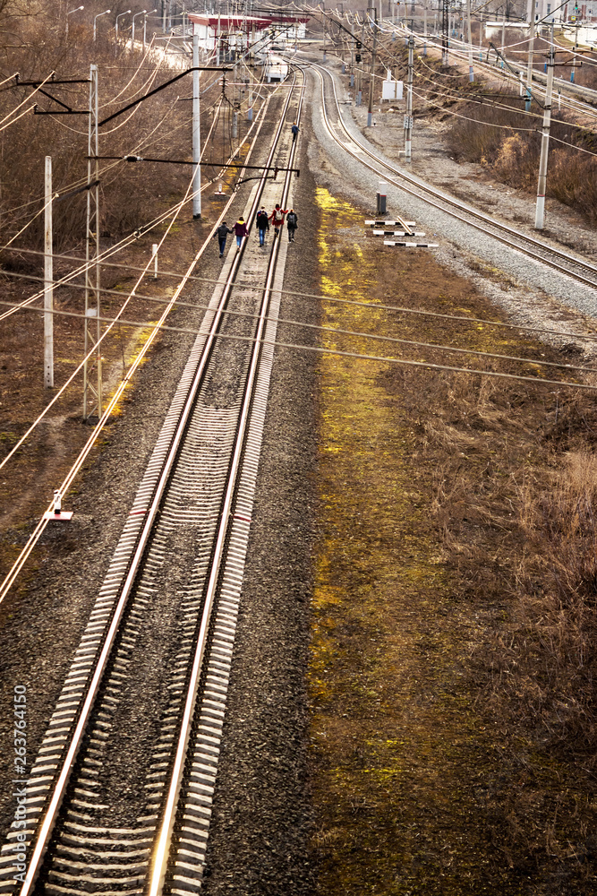 group of teenagers or schoolchildren walking on the train tracks