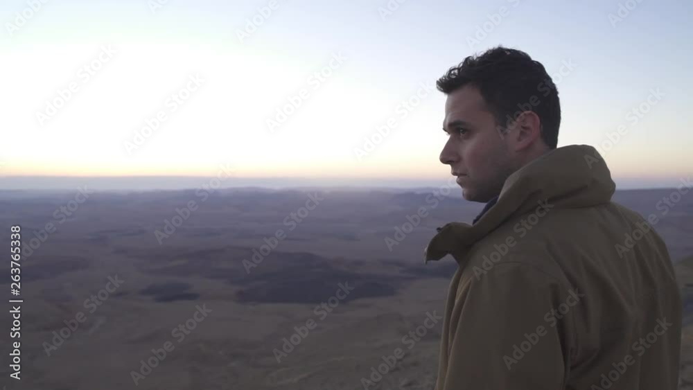 Man standing on a mountain top looking at the desert view Man standing on a mountain top looking at the desert view