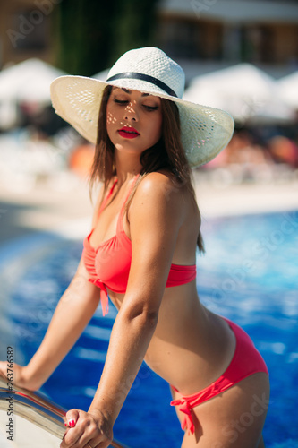 A Sexy lady in a big beach hat get out of the swimming pool