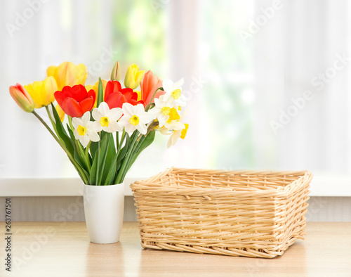  Vase with tulips and an empty wicker basket on the table