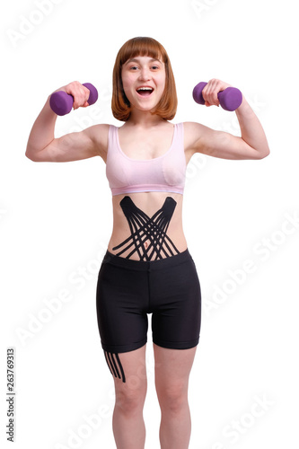 smiling young white girl with kinesio tape on her body goes in for sports with dumbbells isolated on white