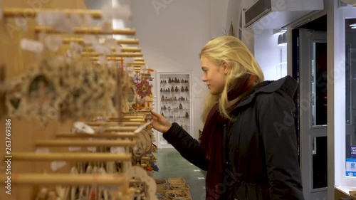 Blonde woman inspecting wooden christmas ornaments inside of a traditional bavarian toy shop. photo