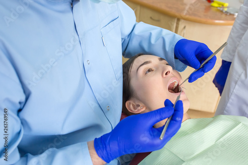 Young woman sits in a dental chair as a patient. People health care, dentistry, medicine concept. Doctor and patient. Teeth dentist with patient in hospital