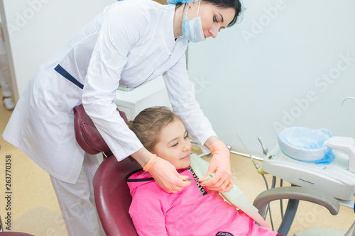 Little girl sits in a dental chair as a patient. Kid health care, dentistry, medicine concept. Doctor and patient