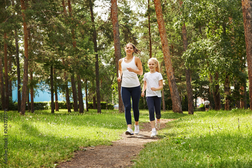 running mother and daughter. woman and child jogging in a park. outdoor sports and fitness family