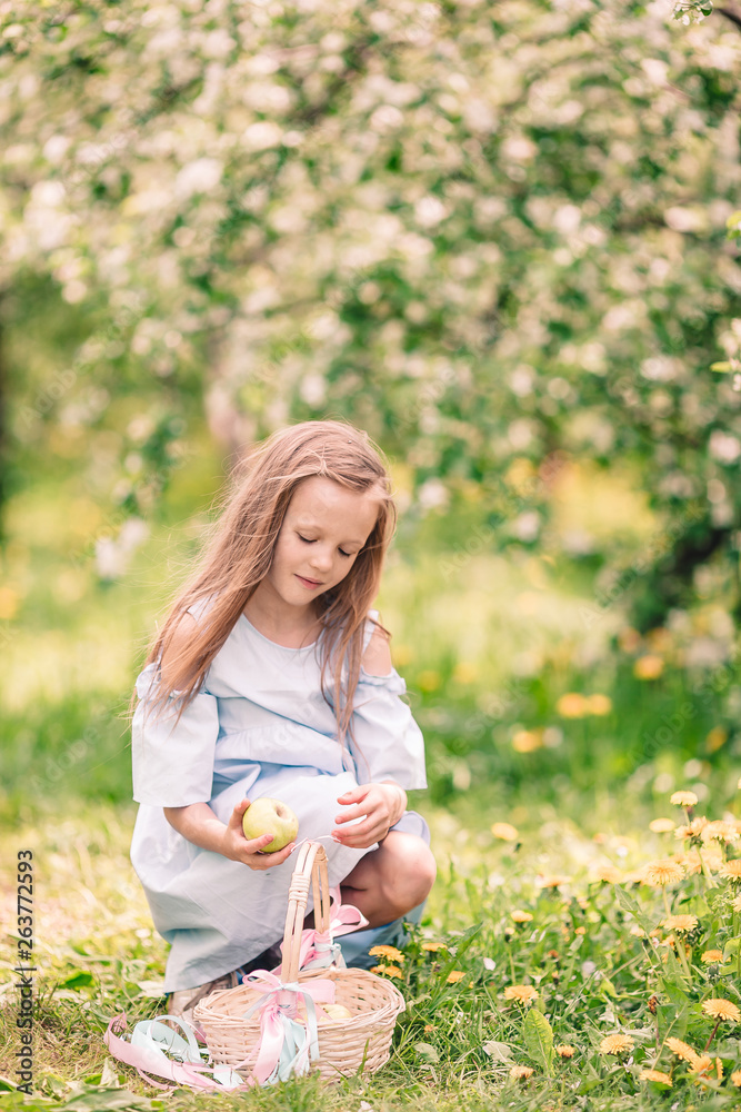 Adorable little girl in blooming apple garden on beautiful spring day Adorable little girl in blooming apple garden on beautiful spring day