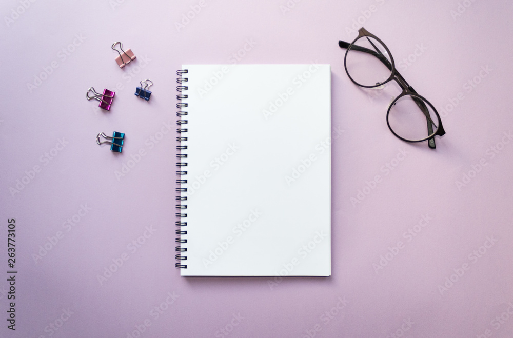 Empty white notebook top view on lilac background close to clips and glasses Empty white notebook top view on lilac background close to clips and glasses
