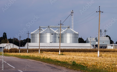 Road and field with mowed corn in front of elevator for grain storage.