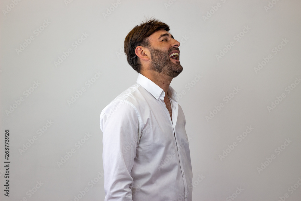 Fashion portrait of handsome young man with brown hair laughing, facing forwards and looking at the side. Isolated on white background. Fashion portrait of handsome young man with brown hair laughing, facing forwards and looking at the side. Isolated on white background.
