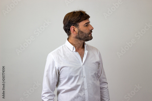 Fashion portrait of handsome young man with brown hair in love, facing forwards and looking at the side. Isolated on white background. © Sergio Barceló
