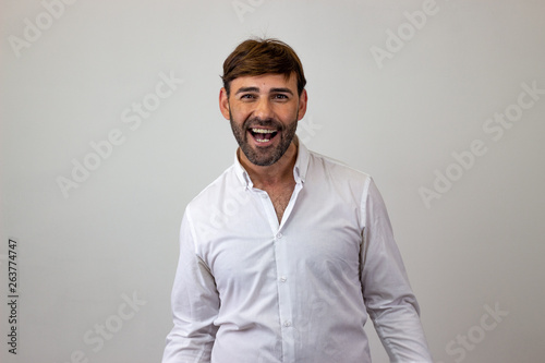 Fashion portrait of handsome young man with brown hair looking happy, looking at the camera. Isolated on white background.