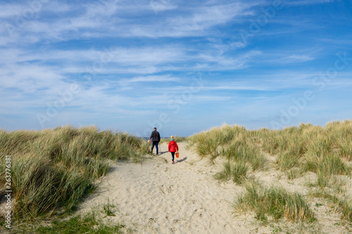 un père et son enfant sur les dunes d'une plage 