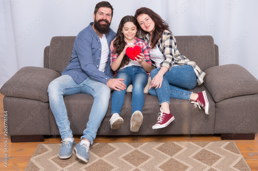 Enjoying every moment together. bearded man and woman with child hold red heart. happy family at home on weekend. mother and father love daughter. little girl with parents. trust and relative bonds Enjoying every moment together. bearded man and woman with child hold red heart. happy family at home on weekend. mother and father love daughter. little girl with parents. trust and relative bonds