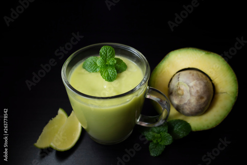 Avocado smoothie withi mint and lime on dark background with copy space for text. Selective focus. Healthy food concept.