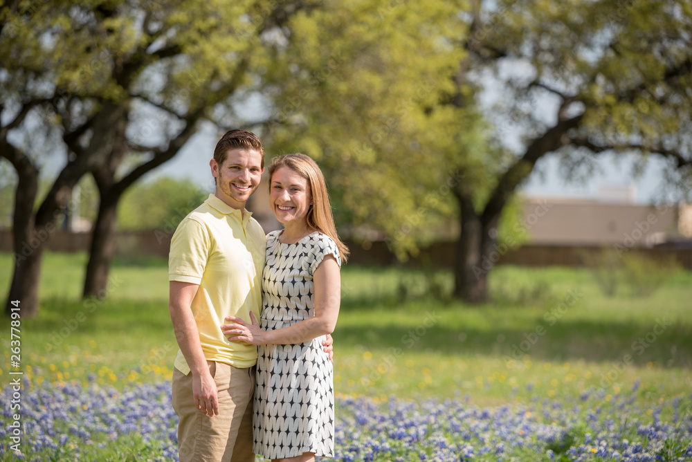 Fototapeta premium Young Millennial Couple Standing During Spring in a Field of Blue Bonnets
