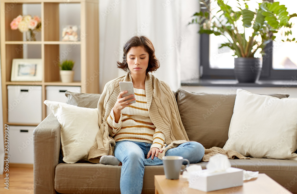 © Syda Productions - technology, health and cold concept - sad sick woman in blanket using smartphone at home © Syda Productions - technology, health and cold concept - sad sick woman in blanket using smartphone at home