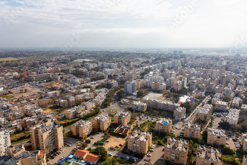 Fototapeta Naklejka Na Ścianę i Meble -  Aerial view of a residential neighborhood in a city during a cloudy and sunny sunrise. Taken in Netanya, Center District, Israel.