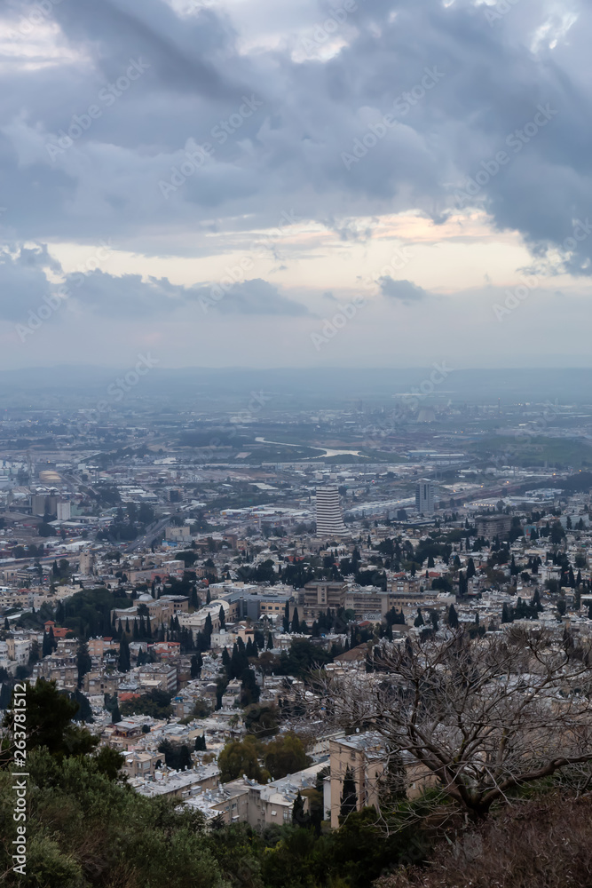 Beautiful view of a city on the coast of Mediterranean Sea during a cloudy sunset. Taken in Haifa, Israel.
