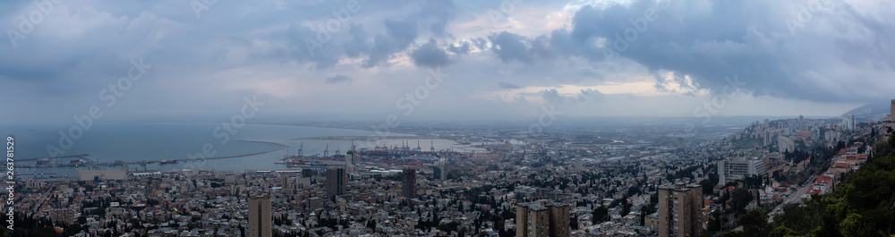 Beautiful panoramic view of a city on the coast of Mediterranean Sea during a cloudy sunset. Taken in Haifa, Israel.