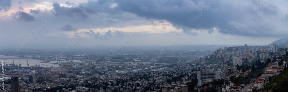 Beautiful panoramic view of a city on the coast of Mediterranean Sea during a cloudy sunset. Taken in Haifa, Israel.