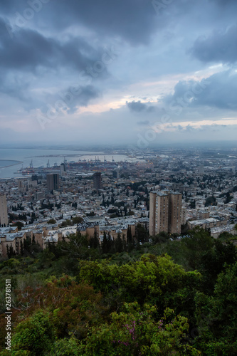Beautiful view of a city on the coast of Mediterranean Sea during a cloudy sunset. Taken in Haifa, Israel.