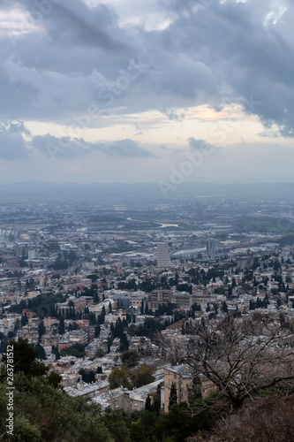 Beautiful view of a city on the coast of Mediterranean Sea during a cloudy sunset. Taken in Haifa, Israel.