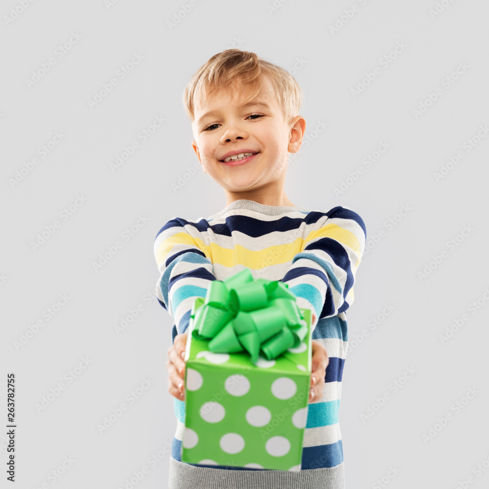 birthday, childhood and people concept - smiling little boy with gift box over grey background birthday, childhood and people concept - smiling little boy with gift box over grey background