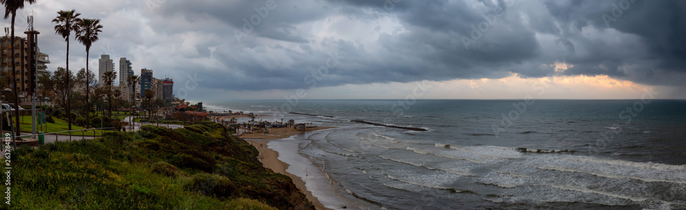 Beautiful view of a sandy beach during a cloudy sunrise. Taken in Netanya, Center District, Israel.
