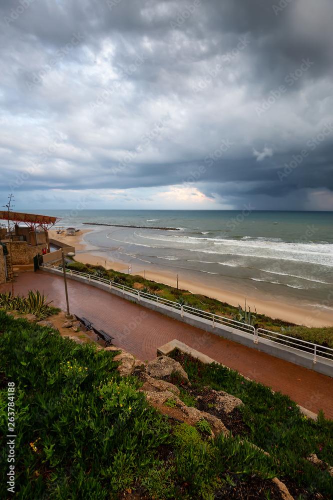 Beautiful view of a sandy beach during a cloudy sunrise. Taken in Netanya, Center District, Israel.