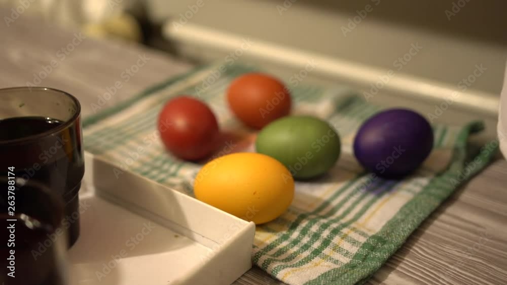 Closeup of painting cups and colorful eggs in the back. The process of making easter eggs. Coocked chicken eggs in different colors. Closeup of painting cups and colorful eggs in the back. The process of making easter eggs. Coocked chicken eggs in different colors.