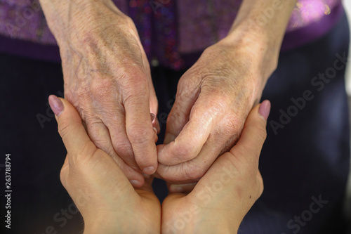Hands of young adult and senior women. Senior and young holding hands outside. Elderly concept