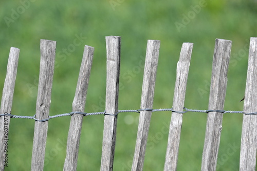 An old, handmade wooden fence. Wooden posts connected to a fence with wire.