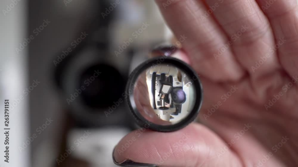 Eye examination, point of view shot, close up magnifying glass while female optometrist works