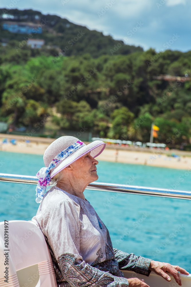 Senior woman enjoys summer vacation in a sea voyage on a pleasure boat.