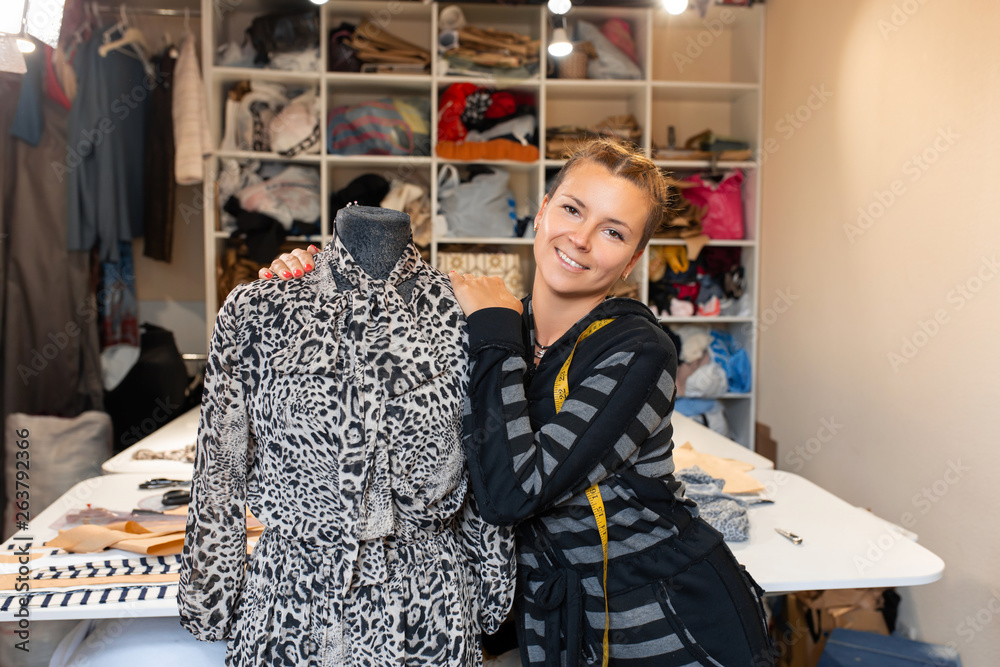 Dressmaker with mannequin as professional fashion designer. female dressmaker adjusting clothes on tailoring mannequin and smiling