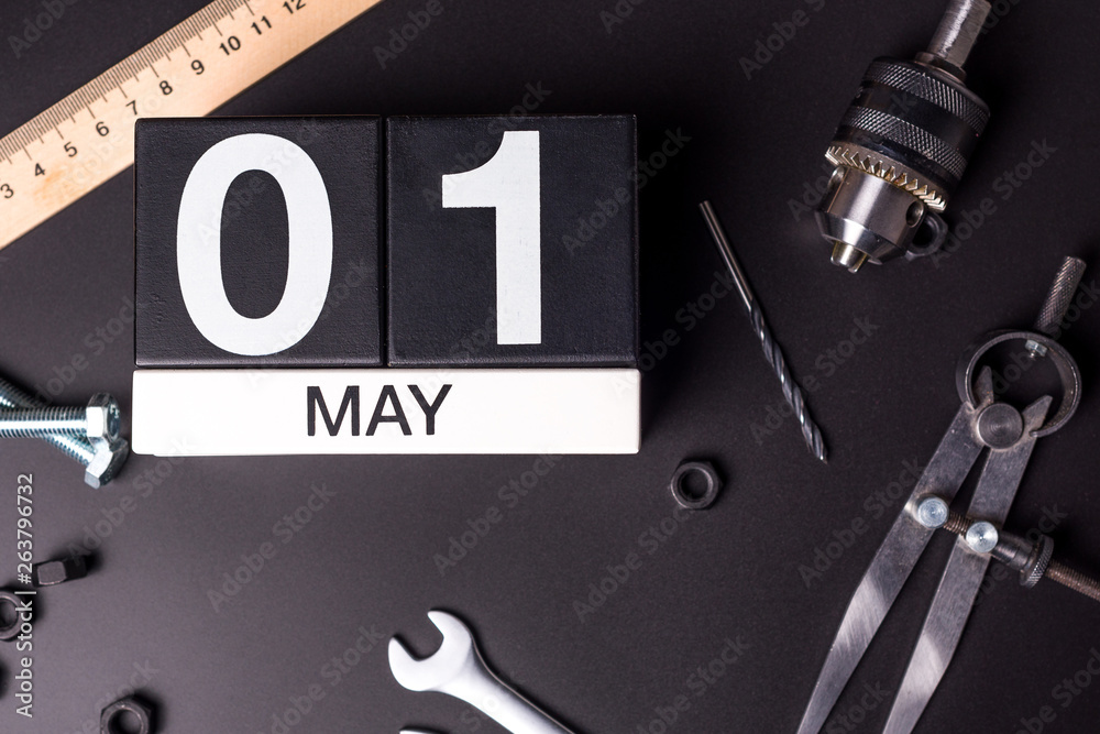 Fototapeta premium Labour day. May 1st. Day 1 of may month, calendar on black background with workers tools