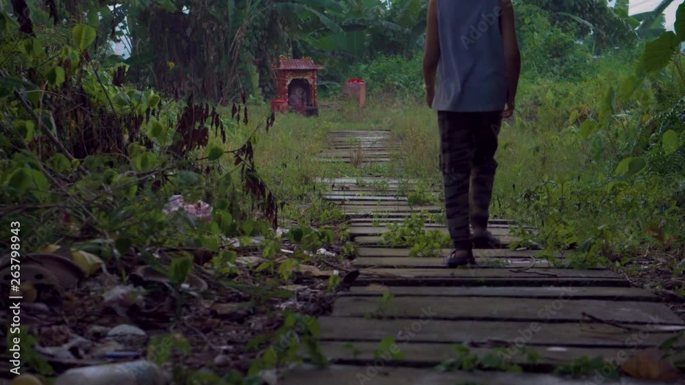 Young Asian boy walking towards a Chinese prayer tomb on a dark gloomy overcast day Young Asian boy walking towards a Chinese prayer tomb on a dark gloomy overcast day