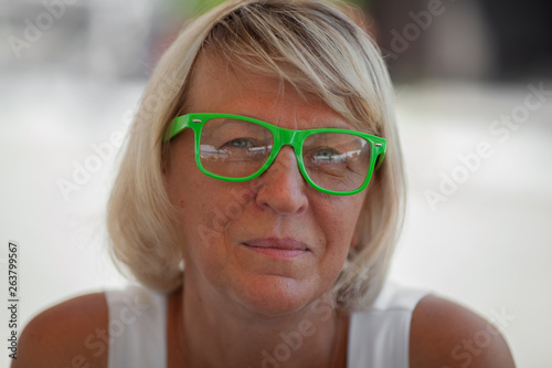 A close up of a middle-aged blond woman in bright-green spectacles photo