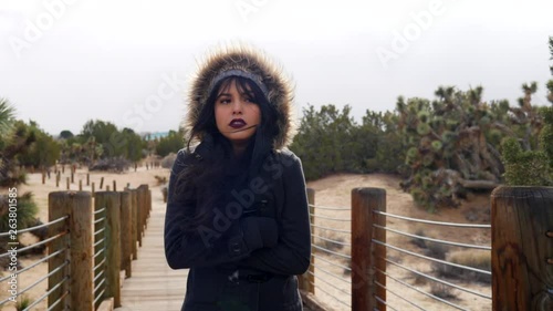 Beautiful young woman shivering in the cold, stormy bad weather with rain drops under cloudy sky SLOW MOTION.