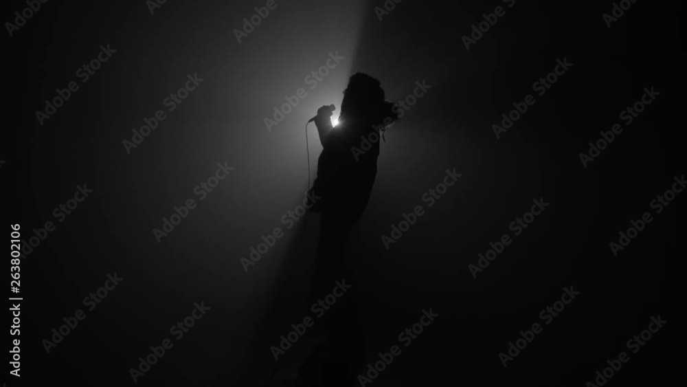 Silhouette of rapper performing with microphone Silhouette of rapper performing with microphone