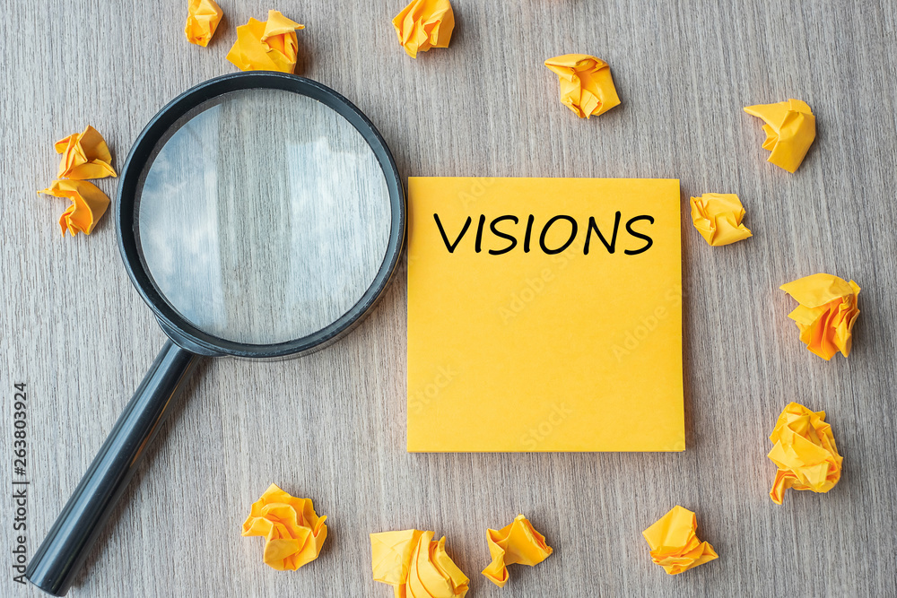 vision words on yellow note with crumbled paper and magnifying glass on wooden table background. SEO, Idea, goal, Strategy, Analysis, Keyword and Content concept