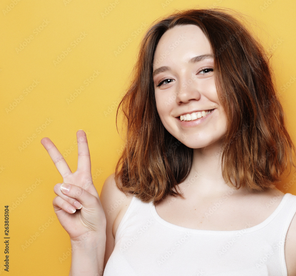 happy girl looking at camera with smile and showing peace sign with fingers happy girl looking at camera with smile and showing peace sign with fingers