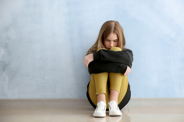 Sad teenage girl near color wall