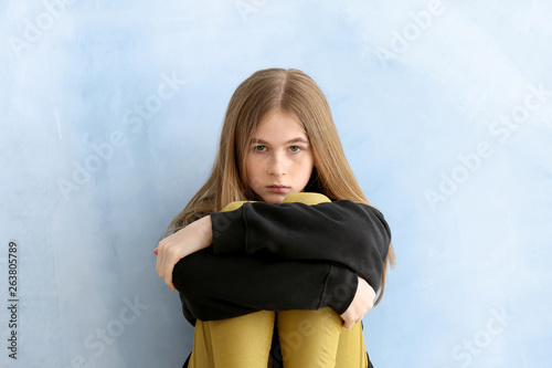 Sad teenage girl on color b...