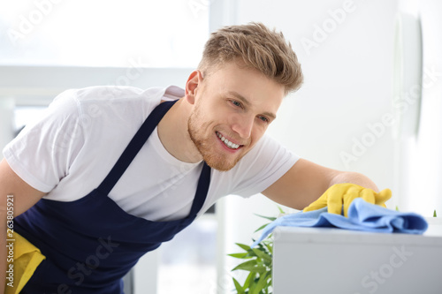 Male janitor cleaning shelf...