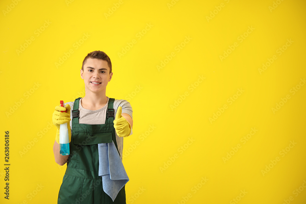 Portrait of male janitor showing thumb-up gesture on color background