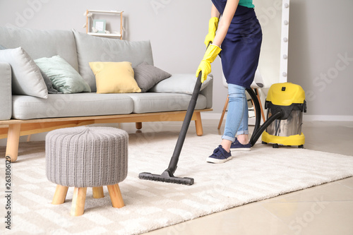 Female janitor with vacuum cleaner in room photo