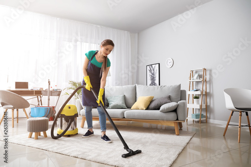 Female janitor with vacuum cleaner in room photo