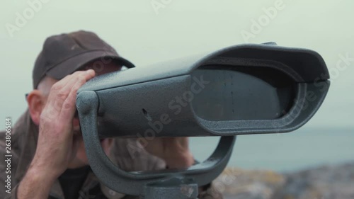 Elderly man looks through binoculars sight seeing viewing at scenic landscape  REAL TIME photo