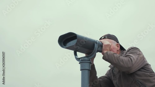 Elderly man looks through binoculars SLOW MOTION LOW ANGLE photo